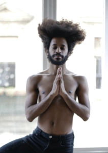 a man stands in a yoga pose next to a window