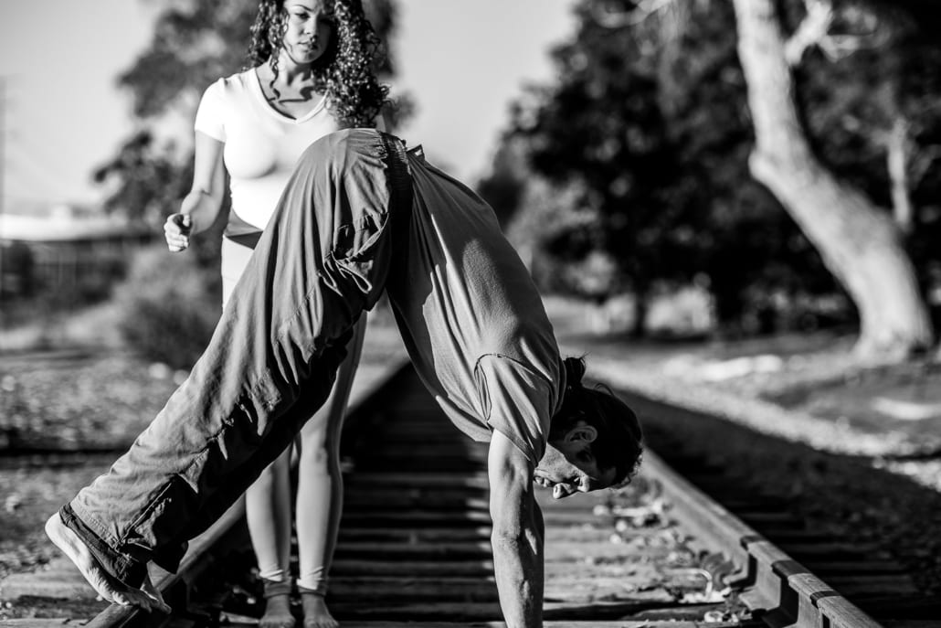 A man and a woman teaching yoga to one another.